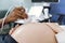 Close up cropped image of hand of male African doctor obstetrician sonographer with transducer, making ultrasound scan