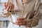 Close-up cropped shot of female artisan pouring dry mixture by hand into measuring transparent glass for creating candle