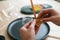 Close-up cropped shot of unrecognizable female artisan using piece of beeswax to create wick for handmade candle at home