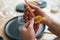 Close-up cropped shot of unrecognizable female artisan using piece of beeswax to create wick for handmade candle at home