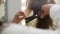 Close-up cropped shot of unrecognizable hairdresser making hairstyle using curling tongs for long hair of female in