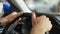 Close-up cropped shot of unrecognizable male customer testing new car at dealership, holding steering wheel in hands