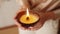 Close-up cropped shot of unrecognizable woman holding burning handmade candle in palms. Closeup of female holding