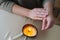 Close-up cropped shot of unrecognizable woman spreading melted wax from burning handmade candle on hand.