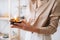 Close-up cropped shot of unrecognizable young woman holding burning handmade candle in hands.