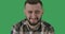 Close-up of crying adult man. Portrait of upset Caucasian handsome guy at green screen background. Chromakey. Concept of