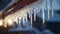 A close-up of a crystal-clear icicle hanging from the edge of a snowy rooftop