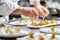 Close-up of a culinary artist using tweezers for precision in plating.