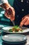 Close-up of a culinary artist using tweezers for precision in plating.