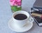 Close-up a cup of black coffee on white table with pink flower, lipstick, smartphone and grasses woman lifestyles