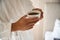 Close up of cup of coffee in hands of man wearing bathrobe in hotel room