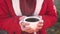 Close up of cup of coffee in woman\'s hands. Unrecognizable female holds hot mug of drink, standing in garden.