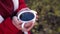 Close up of cup of coffee in woman's hands. Unrecognizable female holds hot mug of drink, standing in garden.