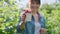 Close-up of cup with ripe raspberries in hands of woman in summer garden