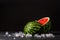 Close-up of a cut round ripe watermelon on a black background. Refreshingly sweet berry with small black seeds on the
