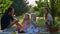 Close up of cute blonde little girls on family picnic with parents in summer. Caucasian children are eating fruits