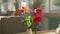 Close-up. Cute bouquet of red roses and freesia in a vase on a table on a sunny summer day in a cafe