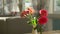 Close-up. Cute bouquet of red roses and freesia in a vase on a table on a sunny summer day in a cafe