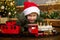 Close-up of a cute boy in a Christmas hat playing with a magic toy train at the Christmas tree.