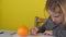 Close-up of cute caucasian serious girl draws an orange