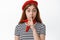 Close up of cute female model in french red beret hiding a secret, making shh shush sign, press finger to lips, ask to