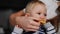 Close-up cute little baby girl biting sour lemon in hand of unrecognizable mother. Caucasian parent giving citrus fruit