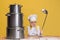 Close-up cute little boy in white cook uniform and huge chef& x27;s hat at kids kitchen with big pans  on yellow