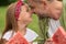 Close up of cute little girl and her loving dad touching noses while eating watermelon, family having a picnic in the
