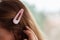 Close up of a cute, pink, girly hairpin on a blonde hair. Blurry background