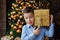 Close-up of a cute surprised boy holding a gift in an ash-wrapped street. A child on the background of a Christmas tree with a