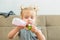 Close up cute toddler girl pouring natural yogurt from plastic bottle to toy cup at home . Healthy diet eating habits. Child self-