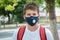 Close up cute young boy with protective mask on his face. Teenager in white t shirt wearing medical mask to protect from corona