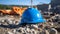 Close up of a cyan Working Helmet on Gravel. Blurred Construction Site Background