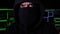 Close-up, cyber hacker with hood and covered face looks at the camera with serious look.