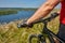 Close-up of the cyclist holding bicycle on the meadow in the countryside against beautiful landscape.