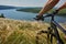 Close-up of the cyclist holding bicycle on the meadow in the countryside against beautiful landscape.