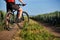 Close-up of cyclist man legs with mountain bike on the path of the green field in the countryside.
