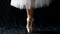 Close-up of dancing legs of ballerina wearing white pointe on a black background