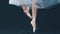 Close-up of dancing legs of ballerina wearing white pointe on a black background