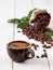 Close-up of dark coffee cup with espresso, roasted coffee beans in the bag of burlap, on white wooden background. Near coffee