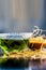 Close up of dark green colored herbal and aryurvedic syrup of khus or vetiver grass in a glass bowl with raw dried khus.