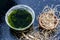 Close up of dark green colored syrup or extract of dried vetiver grass pr khus in a glass bowl on wooden surface with raw khus.