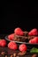 Close-up of dark plate with pieces of brownie with raspberries and mint leaves, with selective focus, black background, vertical,