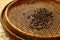 Close up of  dark roasted coffee beans on wicker basket before sieving for home-brew coffee