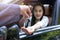 Close up of dealer giving key to new owner car. New car. Auto dealer giving woman automobile key for test drive on country road.