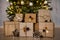 Close up of decorated gift boxes under christmas tree over concrete wall