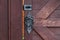 Close-up on a decorative forged Handle and bolt in antique style with a twisted pattern on a brown wooden door. Construction and