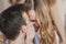 Close up defocused portrait of young attractive romantic couple hugging and kissing, laying down on a bed, being loving with each