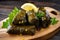 Close-up of delectable stuffed grape leaves with appetizing filling served on a rustic wooden platter garnished with lemon wedges