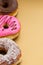 Close up of a delicious assorted donuts with pink, chocolate, coconut, peanut glazed accommodated in one line over a